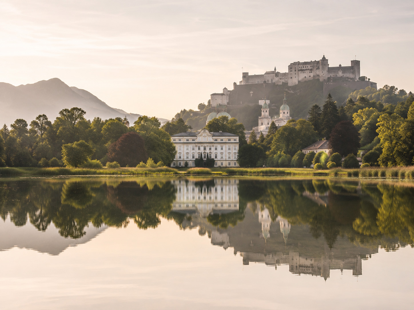Herrenhaus mit Spiegelung im See in ruhiger Umgebung, inspiriert von der eleganten Atmosphäre Salzburgs.